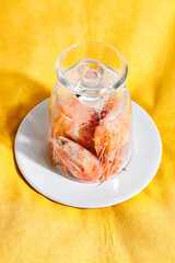 Frozen shrimps in glass on yellow background.Conceptual food