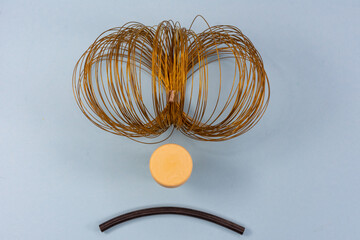 Tangle of thin brass wire and objects for simulating of a discontented face