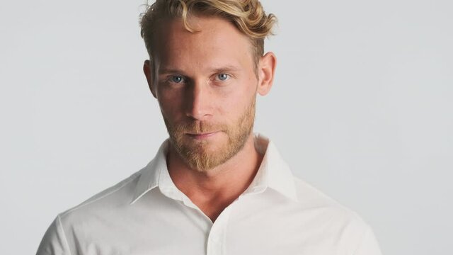 Young handsome blond bearded businessman confidently looking in camera over white background