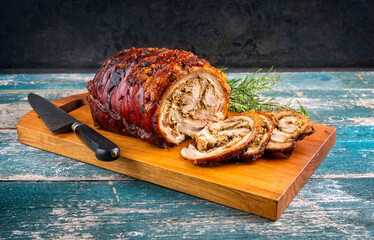 Traditional Italian Porchetta arrotolata pork meat sliced and as piece with herbs offered as...