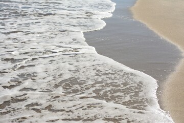 Sea waves running on the sandy beach, close-up