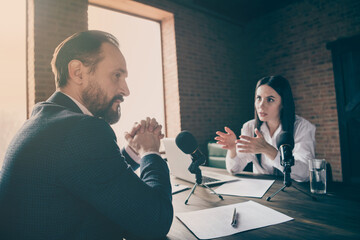 Photo of two people colleagues aged businessman business lady journalist press conference ask political questions speak microphone wait answer sit modern office indoors