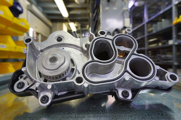Fototapeta premium Cooling system pump of a modern car, in the background a spare parts warehouse is blurred.