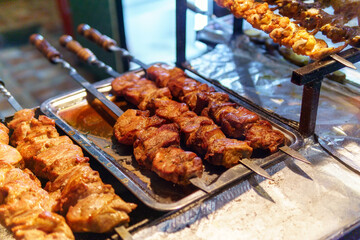 kababs are being grilled with heat in barbeque with metal skewers,at evening for sale as street food