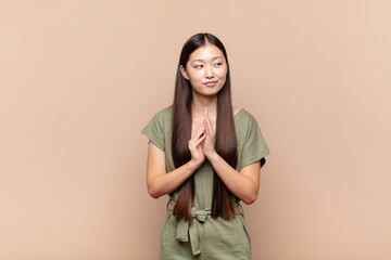 asian young woman feeling proud, mischievous and arrogant while scheming an evil plan or thinking...