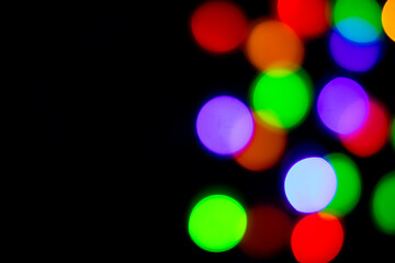 A brilliant glowing background side on black. The glitter light bokeh for the New Year and other holidays.