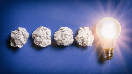 Idee als Glühbirne und Papierkugeln
