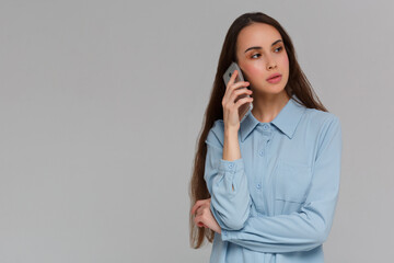 Cheerful young woman talking on mobile phone isolated on a gray background