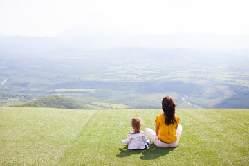 Naklejka na ściany i meble Mutter sitzt mit Kind auf einem Hügel
