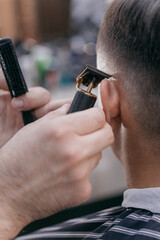 closeup hairdresser cuts guy's hair with clipper