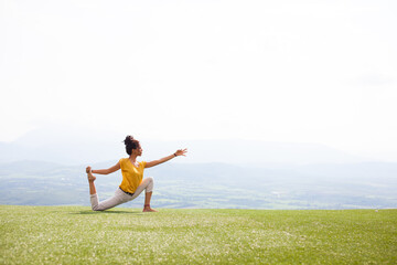 Beautiful woman doing Yoga outside on a hill with a view - 379447287