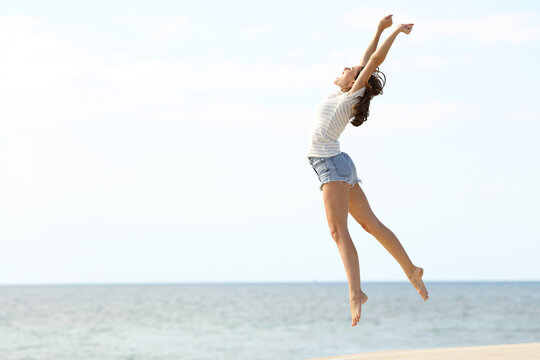 Excited woman with long legs jumping on the beach