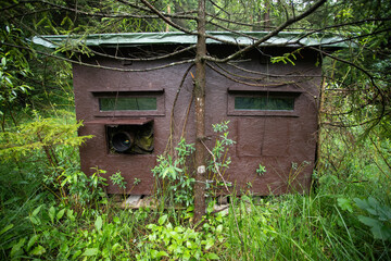 Wildlife photography blind for wild animal observation in summer nature. Wooden hide used by...