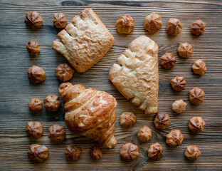 Homemade custard profiteroles laid out on a wooden background.