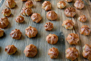 Homemade custard profiteroles laid out on a wooden background.