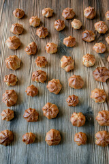 Homemade custard profiteroles laid out on a wooden background.