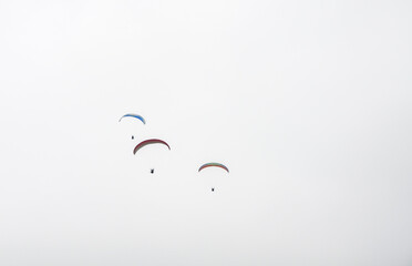 A man is flying on a paraglider in clouds and fog. Summer sports, active lifestyle, activity in mountains 