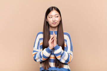 asian young woman feeling proud, mischievous and arrogant while scheming an evil plan or thinking...