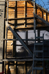 Construction of a wooden house with a large window on which the setting sun is shining.