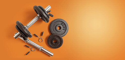 Obraz na płótnie Canvas Metal dumbbell set. Isolated on orange background. Gym, fitness and sports equipment symbol. top view. space copy