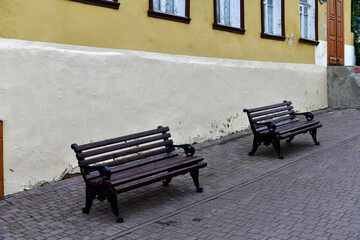 Fototapeta na wymiar two brown benches on an old street