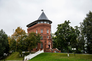 Fototapeta na wymiar vintage red brick watchtower in the park among the trees