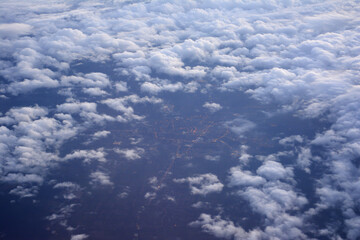 Lights of the evening city through the clouds, view from the plane