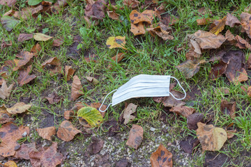 Used single use medical face mask on the ground floor. Environmental Pollution.