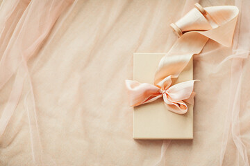 Gift boxes with hand dyed silk ribbon with bow on wood spool on light pink  fabric with folds background and copy space