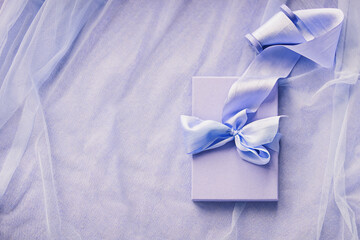 Gift boxes with hand dyed silk ribbon with bow on wood spool on purple fabric with folds background and copy space