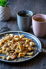 Fluffy, gluten-free, shredded pancake / kaiserschmarrn served with halvah spread, banana, walnuts, and grated chocolate placed on a decorative plate and teacups at the background
