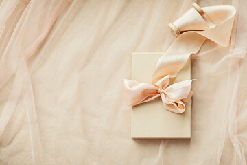 Gift boxes with hand dyed silk ribbon with bow on wood spool on pink beige fabric with folds background and copy space