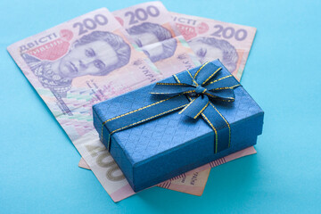 A blue gift box lies on top of banknotes. Shopping concept in Ukraine