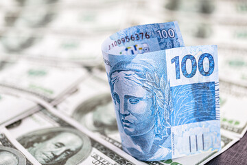 detail of a banknote of one hundred reais from brazil, trapped between banknotes of 100 american...