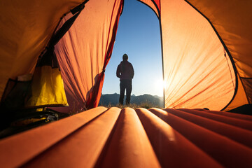 A woman looking at the sunrise during an camping adventure in the mountains.