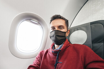 Fototapeta na wymiar Male passenger in protective medical mask are waiting for the plane to take off. Covid pandemic and spreading of desease by airlines concept