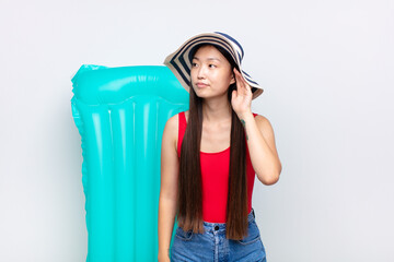asian young woman looking serious and curious, listening, trying to hear a secret conversation or...