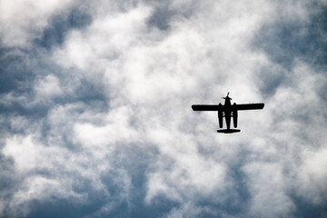 Biplane flying in the cloudy sky. Retro style, airplane silhouette, upward view