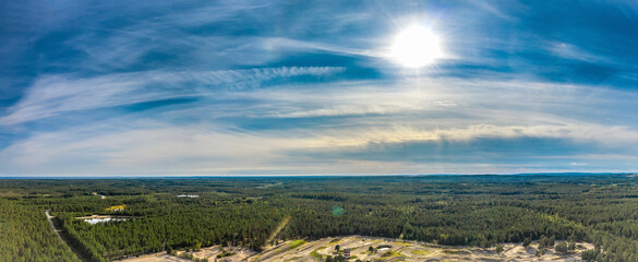 Breathtaking Aerial View of Endless Scandinavian green pine tree forest up to horizon line, part of speedway training track below. Sunny summer day. Typical Northern Scandinavia landscape