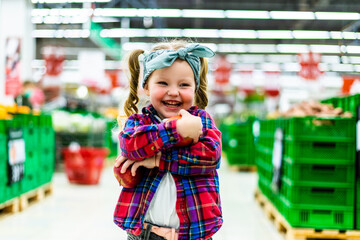 Little girl choosing ripe apples in food store or a supermarket
