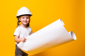 Little girl architect in the construction helmet with a poster isolated on yellow background