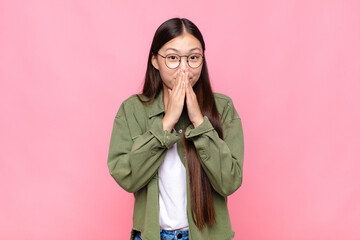 asian young woman happy and excited, surprised and amazed covering mouth with hands, giggling with...