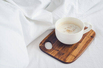 Cup of cappuccino on the bed