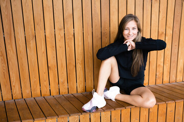 Fototapeta na wymiar Beautiful girl athlete sits on a wooden bench