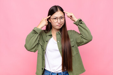asian young woman with a serious and concentrated look, brainstorming and thinking about a...