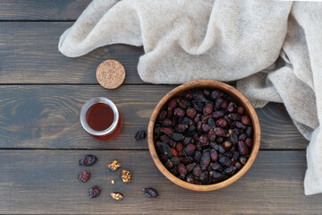 top view of dry rose hips lie in wooden bowl and warm vitamin drink from rose hip stand by, Wool textile lie  around.. Healthy drink in cold season for recovery.