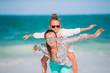 Beautiful mother and daughter at Caribbean beach enjoying summer vacation.