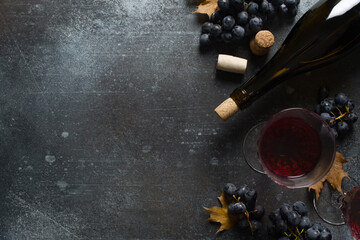 Bunche of black grape and bottle of wine on dark background