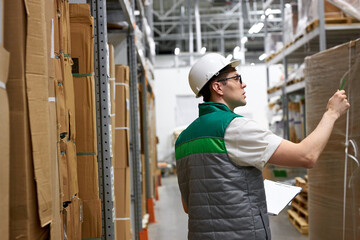 Fototapeta na wymiar concentrated young warehouse worker in production department of modern store, take notes. export, logistics concept