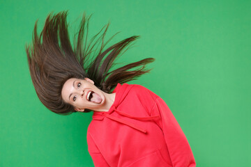 Crazy funny young woman wearing red streetwear hoodie dancing shaking head with fluttering hair...